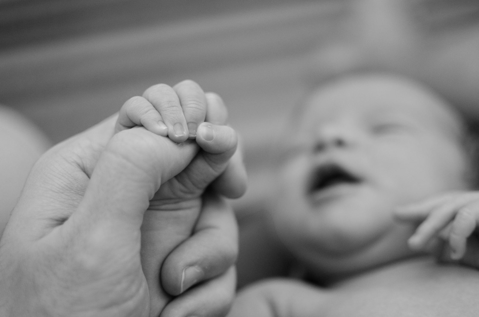 Närbild på en vuxen hand och en bebis hand som håller i varandra