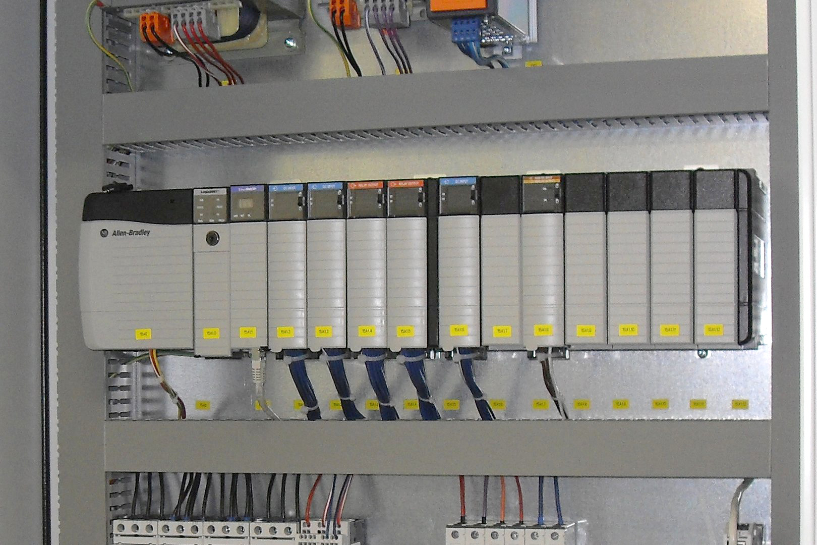 Industriellt styrsystem med Allen Bradley-PLC monterat i ett elskåp med kablar och kopplingsplintar